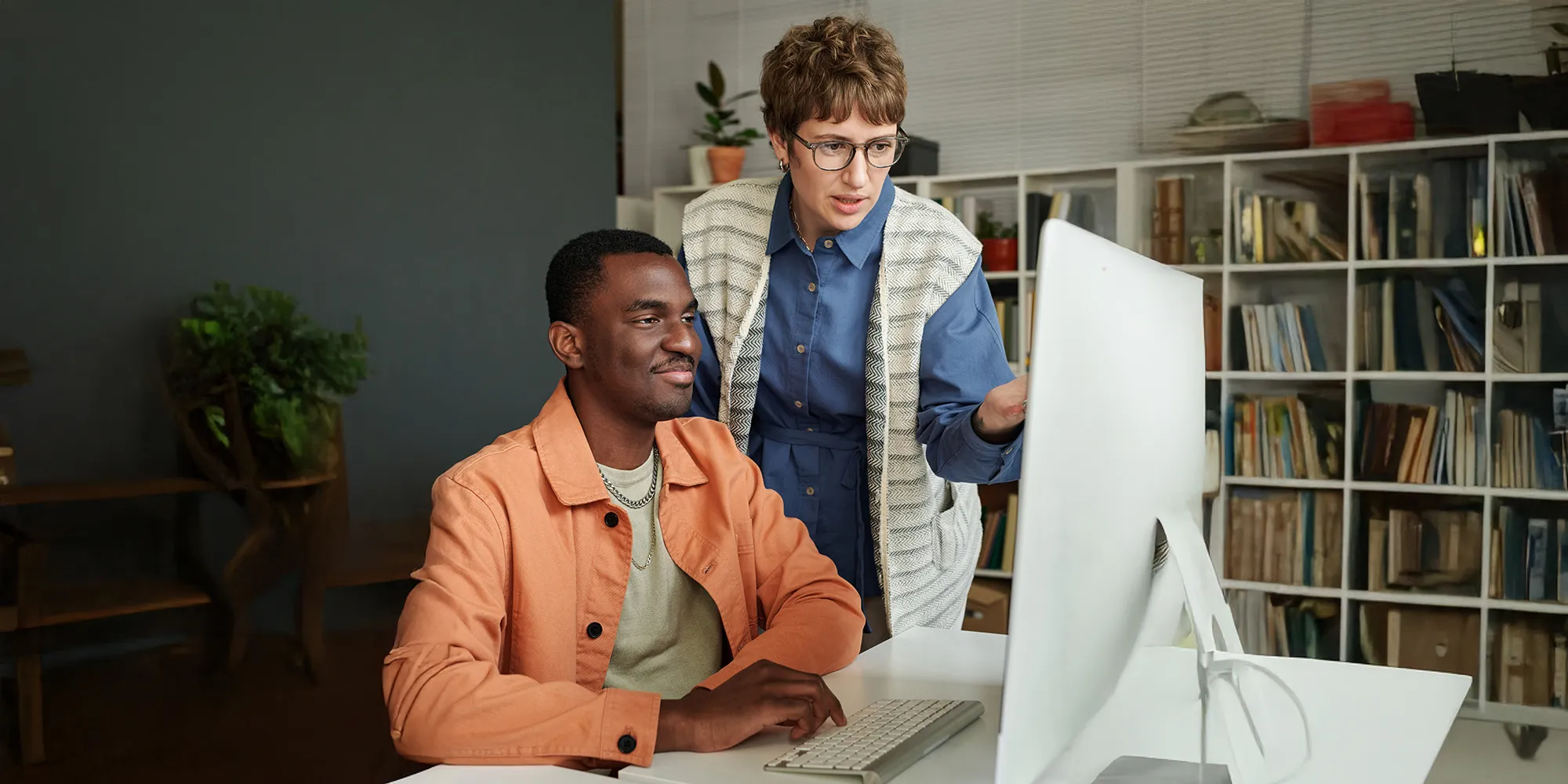 IT consultants discussing technology solutions while working at a desktop computer